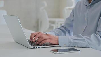 Moving shot Arabian Indian businessman ethnic smiling man working laptop male business employer programmer coding computer program software typing project remote job with mobile phone on office table photo