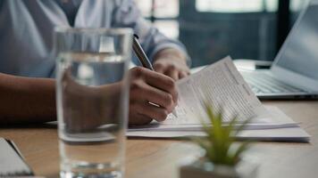 Close up male hands writing exam in class business paperwork with glass of water on office desk unrecognizable man businessman student studying write paper notes document text form insurance summary photo