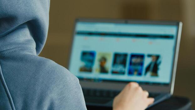 computadora pantalla ver terminado hombro desconocido irreconocible hombre espalda empresario ingeniero programador hacker especialista buscar información en línea Internet navegador escoger película televisión película en sitio web ordenador portátil foto