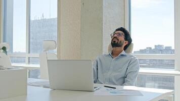 Tired stressed Arabian Indian man businessman upset guy executive manager employer overworked read business documents financial trouble difficult working laptop in office credit debt problem failure photo
