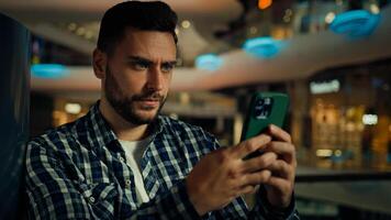 Concentrated pensive caucasian hispanic businessman thinking worker serious man looking at mobile phone screen texting message typing on smartphone chatting online app buying goods in shopping center photo