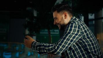 Side view hispanic arabian man stand in shopping mall business center bearded handsome guy client businessman use phone gadget read digital news chatting in mobile messenger make order in online store photo