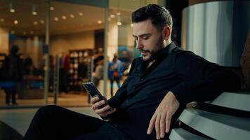 Businessman caucasian man bearded male sit at shopping business center read sms messages on cellphone chatting online in social networks make order by phone use smartphone apps browsing mobile website photo