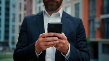 Businessman unknown man stand in city hold phone gadget send messages virtual communication make order online read digital news search media content shopping at internet store use mobile banking apps photo