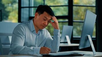 Disappointed angry Asian office manager mature man specialist lawyer banker work with paper documentation read legal documents check error bankruptcy problem negative incorrect result business failure photo