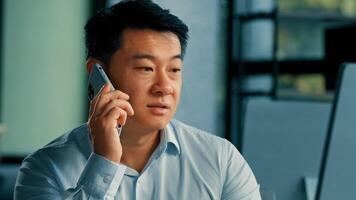 Sad Asian executive worker businessman manager middle-aged korean japanese chinese man answer mobile call work in office speak phone solve business problem distant conversation by 5g cell connection photo