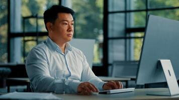 Professional male worker asian korean man successful businessman programmer specialist sit at office desk work with computer software program freelance online job business commerce typing on keyboard photo