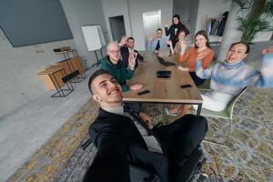 A group of business professionals taking a selfie during a break in an office meeting, capturing a moment of teamwork and collaboration in a modern workplace photo