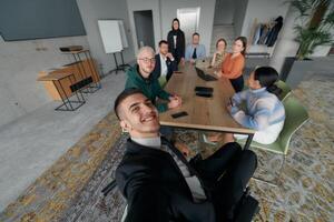 A group of business professionals taking a selfie during a break in an office meeting, capturing a moment of teamwork and collaboration in a modern workplace photo
