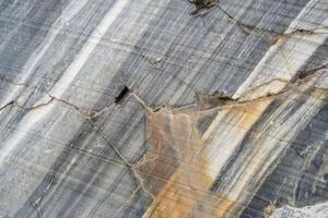The surface of marble reveals intricate natural veins and textures highlighting its rich colors and patterns, found in a quarry setting photo