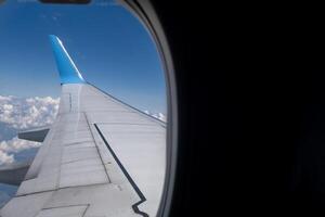 Looking through an airplane window at the aircraft wing during a mid-flight photo