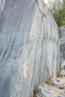 The marble quarry features smooth, polished stone surfaces with natural markings under bright sunlight surrounded by greenery photo