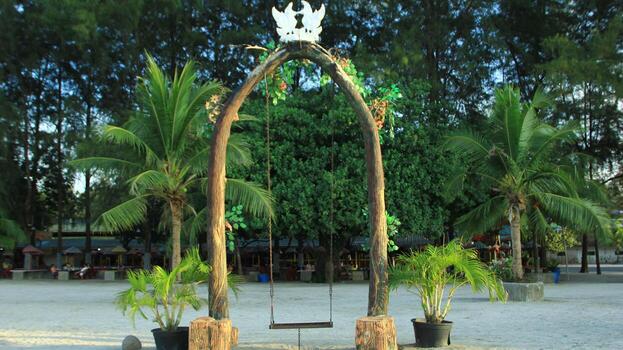 swing on the beach with a backdrop of trees and white sand photo