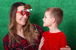 mother and son are preparing for Christmas and New Year. child plays with mom at Christmas. family celebration. green background photo