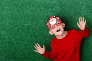cute boy in New Year's souvenir glasses with Santa Claus on a green background laughs and has fun. green New Year background photo