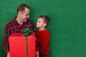 a man with a small son are holding a large gift in cookies on a green background and looking at each other. family congratulations. holidays new year, valentine's day photo