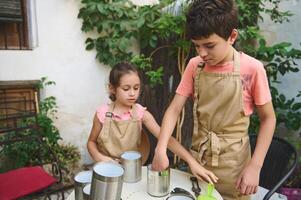 Children gardening together with recycled tin cans in a backyard photo