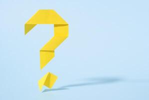 Floating yellow origami question mark with drop shadow photo