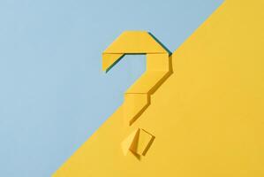 Yellow origami question mark on a diagonal two tone background photo