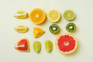 Mixed summer fruits on yellow background in geometric order - Lemon, orange, lime and grapefruit cut into pieces - Minimal trendy concept photo