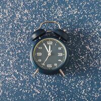 Alarm clock over a cold blue background with scattered snow photo