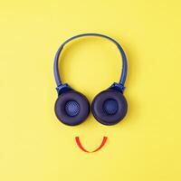 Headphones on a yellow background in the form of a happy face with a smile - Minimalistic composition with a concept about music or a disco or learning in audio photo
