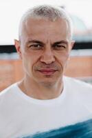 A man with a shaved head and a beard is wearing a white shirt with a blue stripe photo