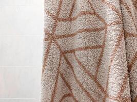 Soft beige towel hanging at bathroom, geometric design, sense of comfort and warmth. Decorative element for home organization, interior design, cozy indoor photo