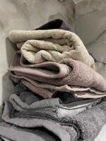 Tidy pile of plush towels in shades of gray and beige. Atmosphere of bathroom, soft textures, light marble backdrop. Decorative background about interior design photo