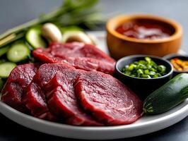 Raw Beef Slices on a Plate with Fresh Vegetables and Assorted Sauces in a Gourmet Presentation photo