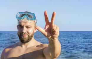 The adult man with the beard squinting and showing a three-finger salute photo