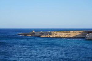 Coastal Cliff Edge Extending into the Blue Sea under Clear Sky photo
