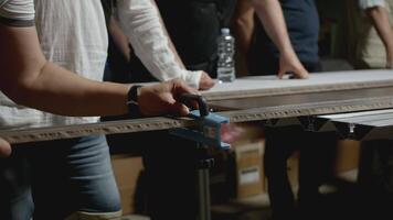 Woodworking master class. Creative. Close-up of man shows group of people how to take measurements on wooden board. Master class in carpentry in industrial workshop video