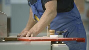 Close-up of carpenter working with wooden board in factory. Creative. Man is working with wooden board on industrial machine. Working as carpenter at woodworking enterprise video