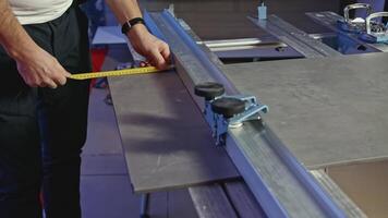 Close-up of man cutting tile products on machine. Creative. Machine with fastening for cutting tiles. Carpenter with measurements divides board or tile video