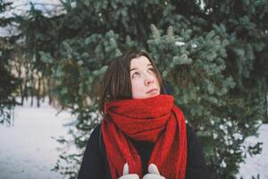 A woman with a red scarf enjoys a snowy winter day in a forest setting beneath a bright blue sky photo