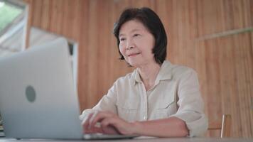 Senior woman studying online, sitting at desk with laptop, reading information, searching for creative ideas, studying cooking online, working remotely, workflow using modern technology. video