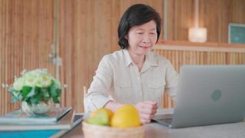 Retired woman sitting reading healthy cooking lessons online. Sitting at desk with laptop. Reading information, searching for creative ideas, learning cooking online, workflow using modern technology. video