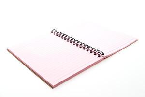 A pink notebook with spiral binding on a white surface photo