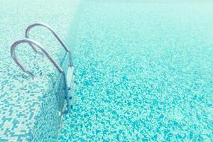 A pool with a ladder and a blue tile floor photo