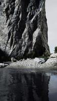 Rugged rock cliff with mountains in the ocean video