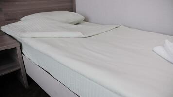 A towel is lying on the made-up bed in the hotel. The room is waiting for guests and guests. video