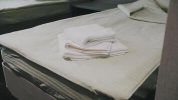A towel is lying on the made-up bed in the hotel. The room is waiting for guests and guests. video
