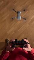 vertical pov first person view Man piloting drone indoors with remote control, hovering over parquet floor. Experience technology, entertainment, and skill in maneuvering quadcopter with precision video