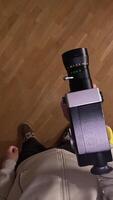 vertical pov First person view Cameraman captures footage with a vintage 8mm movie camera on a parquet floor. Showcasing retro filmmaking. Vintage equipment adds nostalgia video