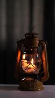 vertical Vintage oil lamp burning brightly, casting a warm glow in a dimly lit room, creating a cozy and nostalgic atmosphere with its soft light video