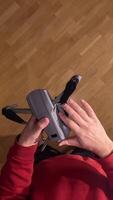 vertical pov, first person view. Man unfolds modern compact folding quadcopter drone. Preparing drone for flight. Person mounting propellers on a gray foldable quadcopter drone, flight video