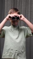 vertical Young boy holds binoculars to his eyes, engaging in imaginative exploration and discovery, his face lit with a sense of wonder and adventure video