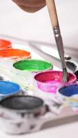 vertical kid little girl Artist dips a brush into vibrant pink paint, selecting color from a colorful palette. The creative process unfolds in a studio filled with artistic tools and inspiration video
