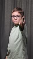 vertical portrait of a boy with a wooden sword in his hand. The boy looks at the camera and points the sharpest sword at the camera. A boy with glasses plays a knight, a warrior with a sword video